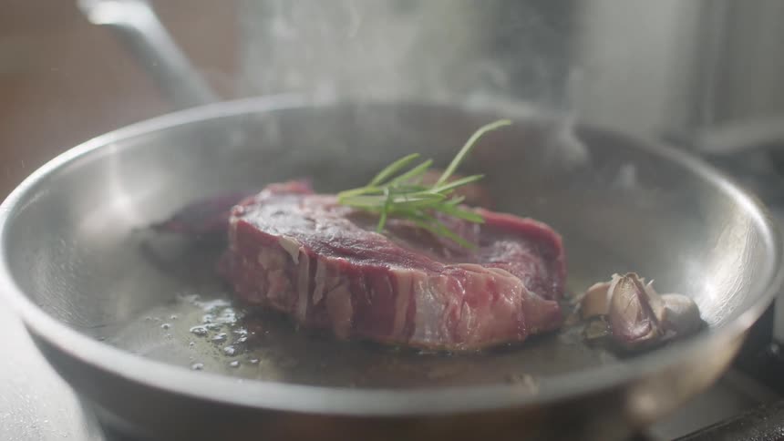 Meat is frying in a pan on a stove