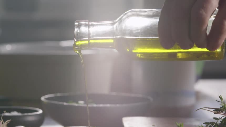 A person pours some cooking oil into a bowl