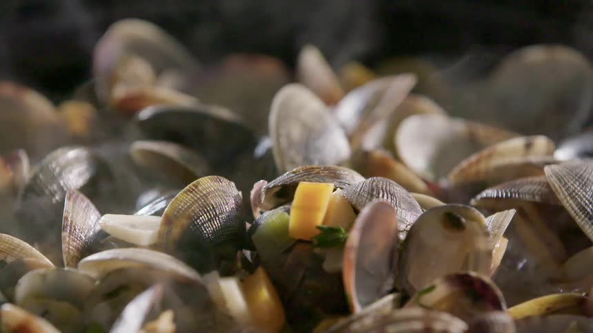 Clams stewing and smoking in vegetables and water