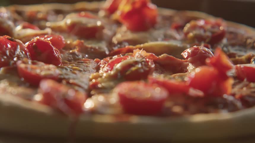 A pizza covered in vegetables steams in a kitchen