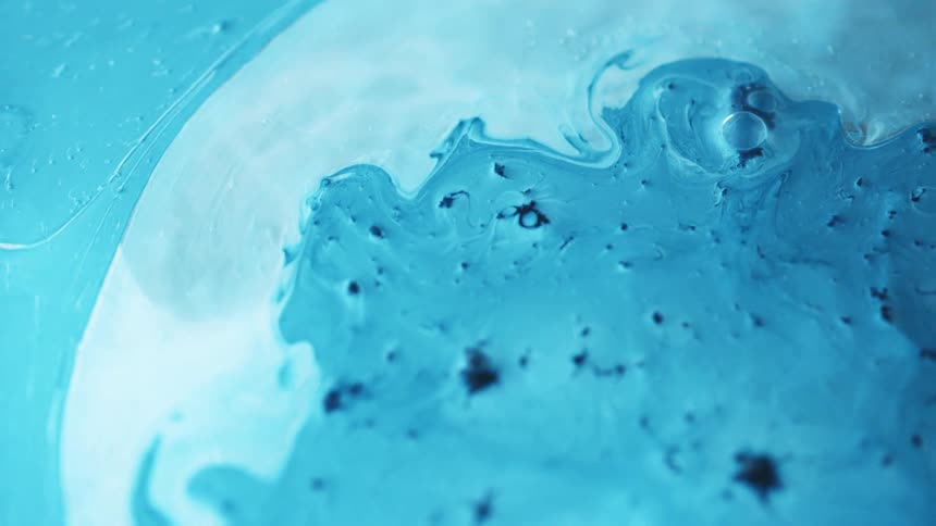 Drops of blue dye are added to a container of liquid