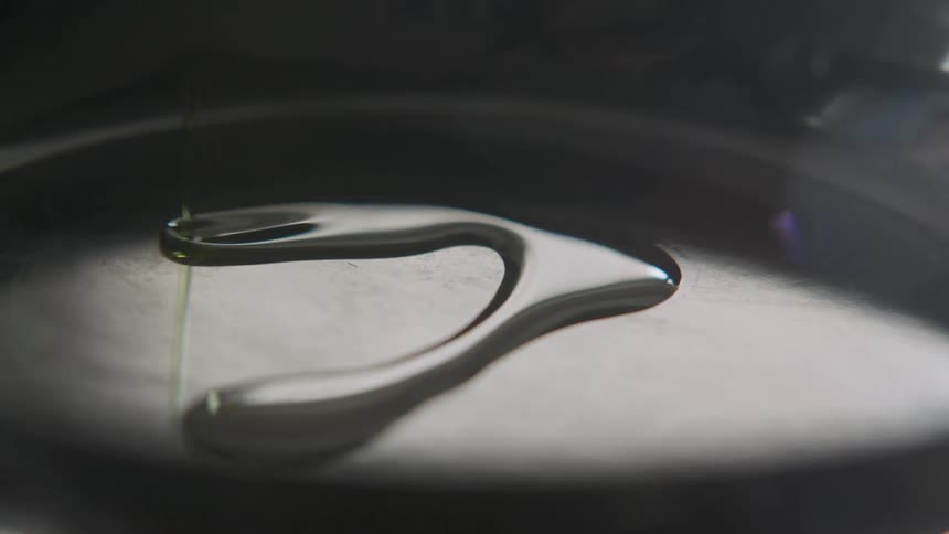 Oil being poured in a round metal pan