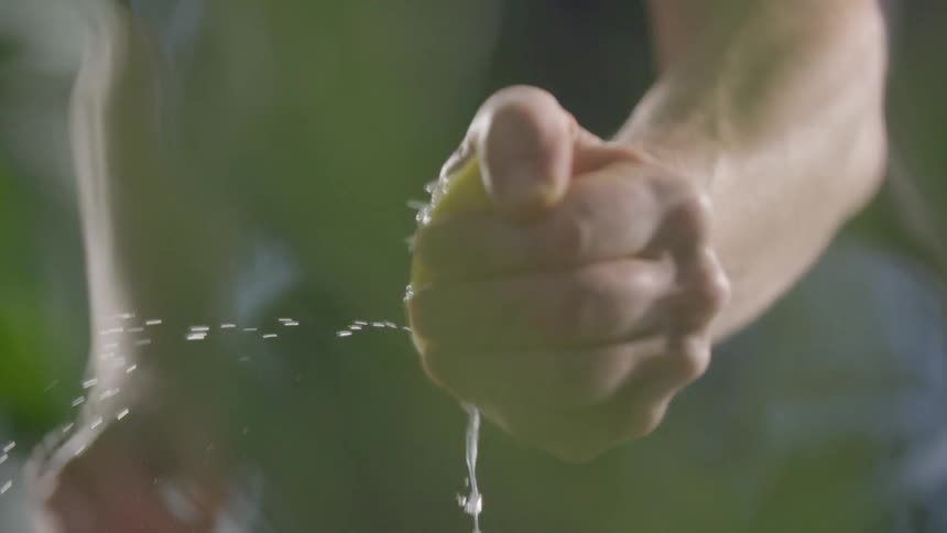 Man squeezes a lemon with his hands on a kitchen