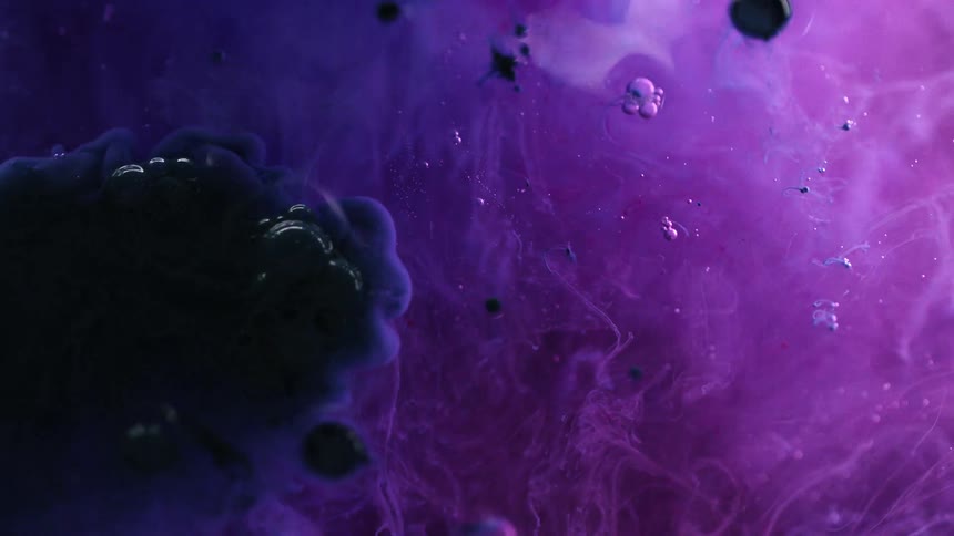 Darker colored fluid added to purple liquid spreads creating bubbles