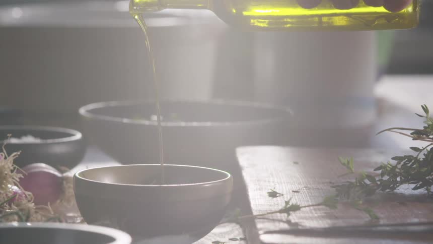 Man pours vegetable oil in a bowl on the kitchen