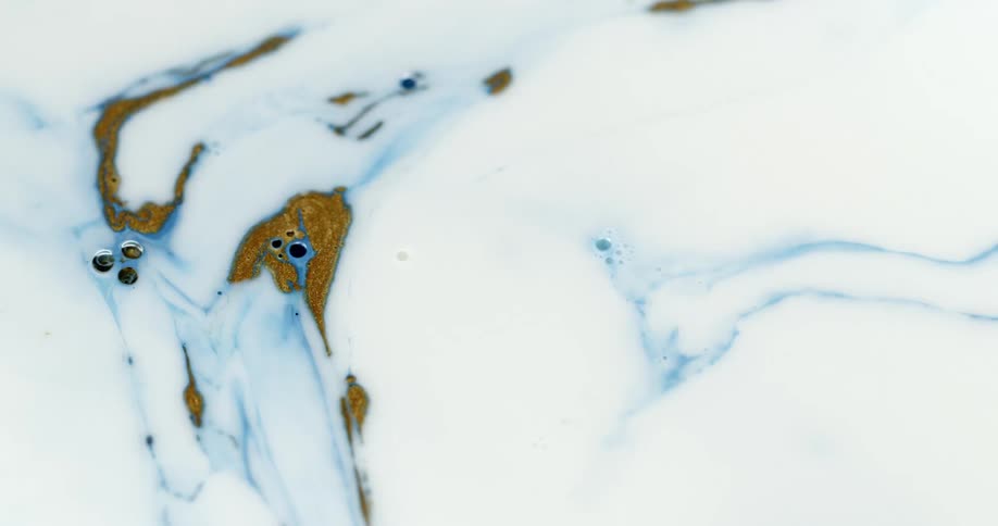 Blotches of colorful inks floating on a white liquid