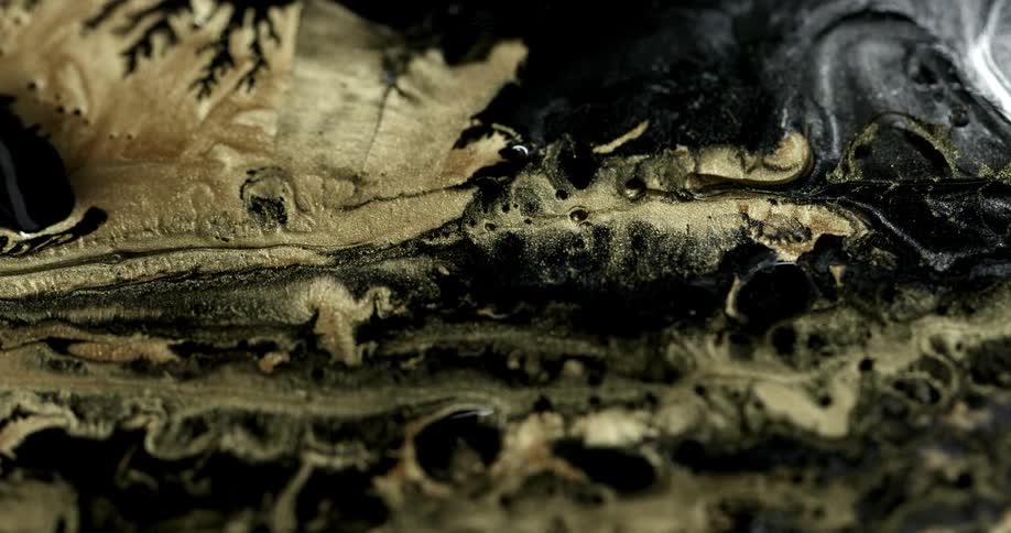 Gold liquid oozes into a black and gray liquid