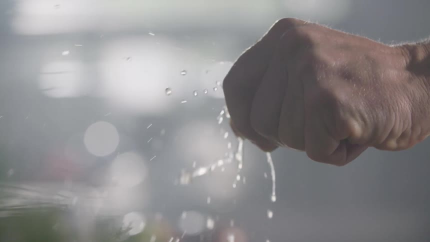 A man squeezes a lime and juice squirts all over