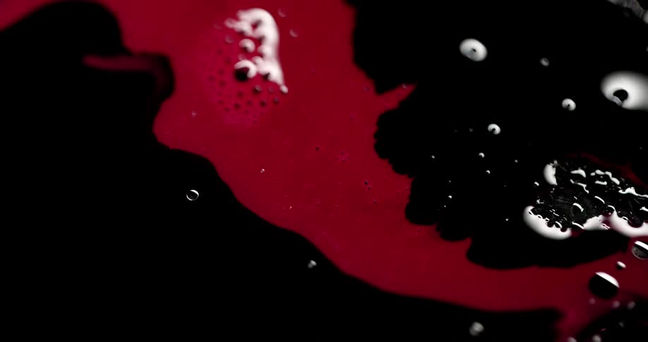 Bright red ink over dark black with bubbles reflecting white light
