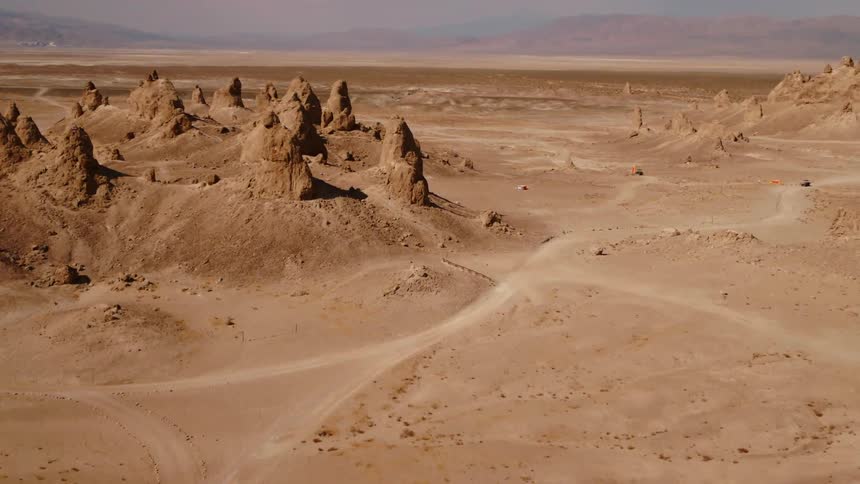 Dirt roads wind among rock outcroppings in desert stretching to hazy mountains on the horizon