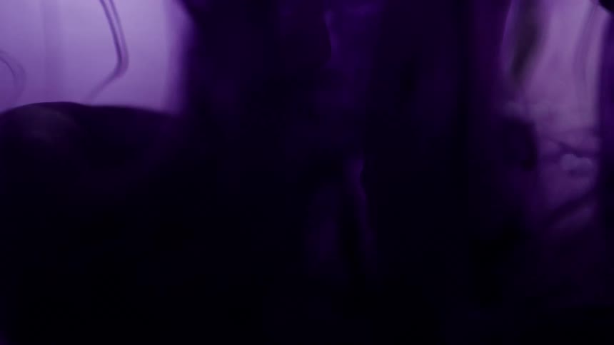 Purple dye drips down the side of a vat of liquid