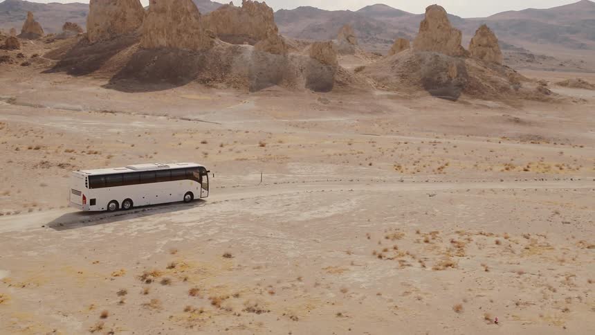 Aerial view of a bus driving on a dirt road in the desert