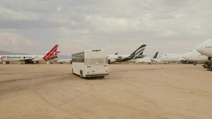 Bus drives around an airfield around commercial airplanes and airliners
