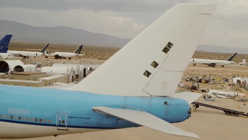 Numerous jetliners sit in the desert as mountains sit in the distance