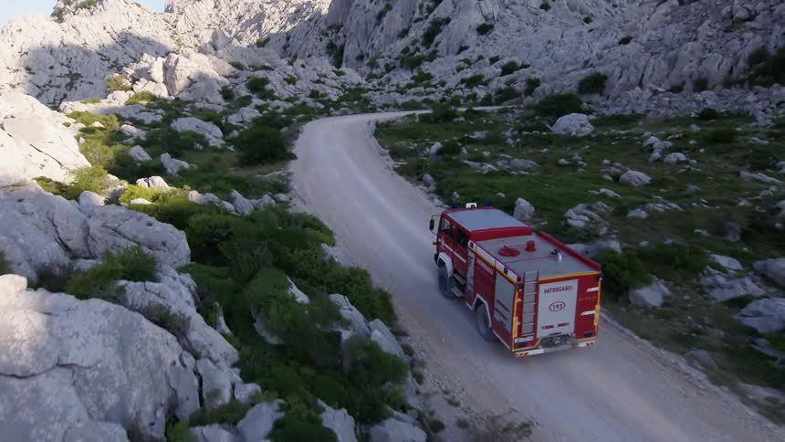 Aerial view of a fire truck driving down a road in a mountainous area