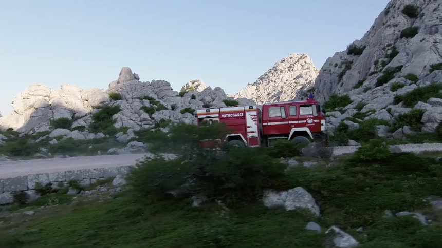 Fire truck drives on gravel road through rugged mountains