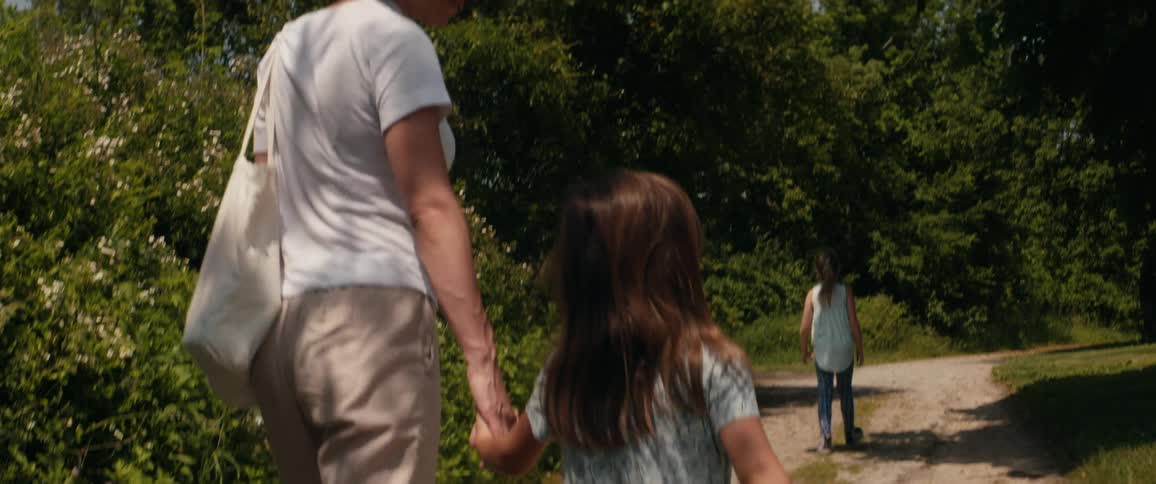 A mother walks along a rural pathway with her two daughters