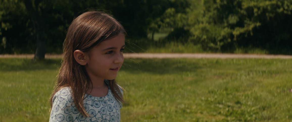 A young girl smiles as she stands outdoors