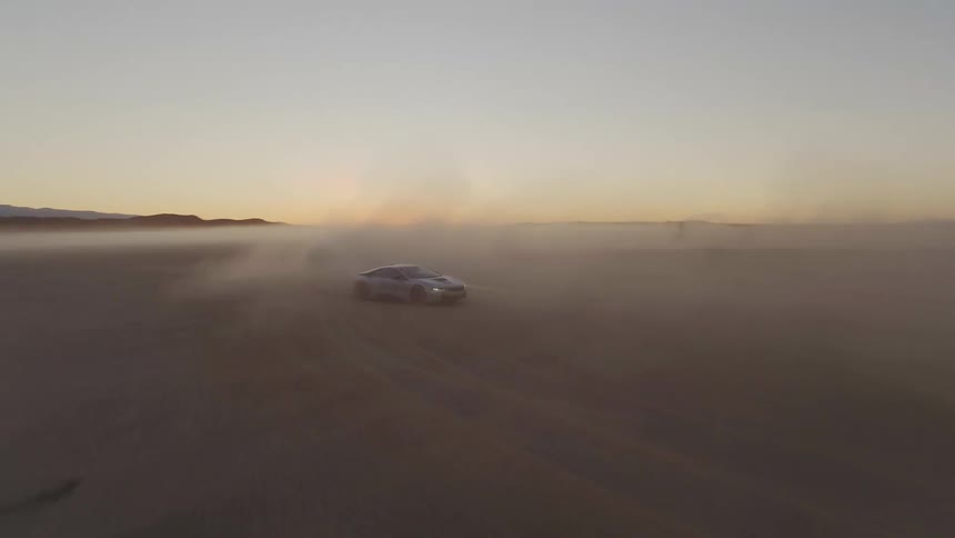 Sports car racing and drifting on the desert leaves a trail of dust at sunset