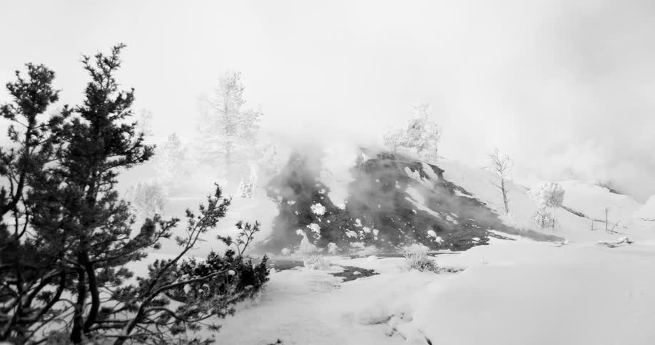 Steam from a river melts the snow on a hill during winter