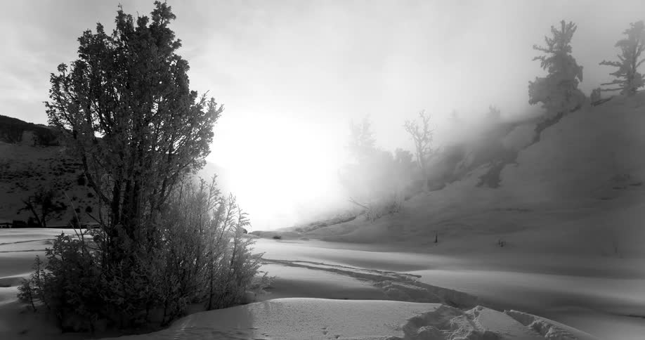 Mist rolling over snow covered hills at sunset