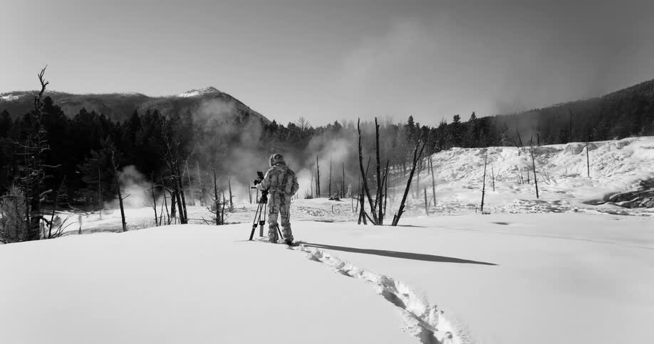 A person sets up a camera and tripod on a snow covered mountain