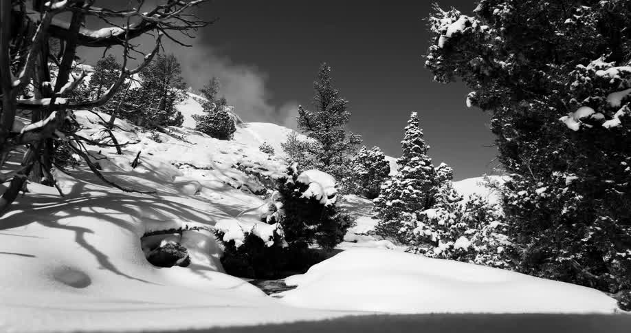 The clouds flow over the snow covered mountains