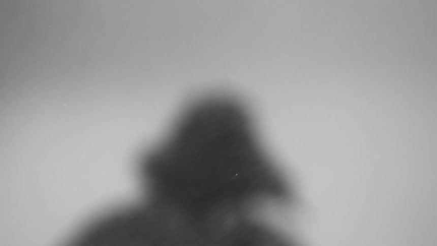Out of focus shot of a man in full winter gear walking on a snow storm