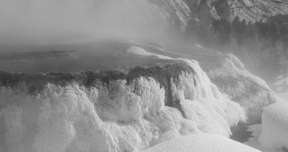 Steam rises around a big rock covered in frost
