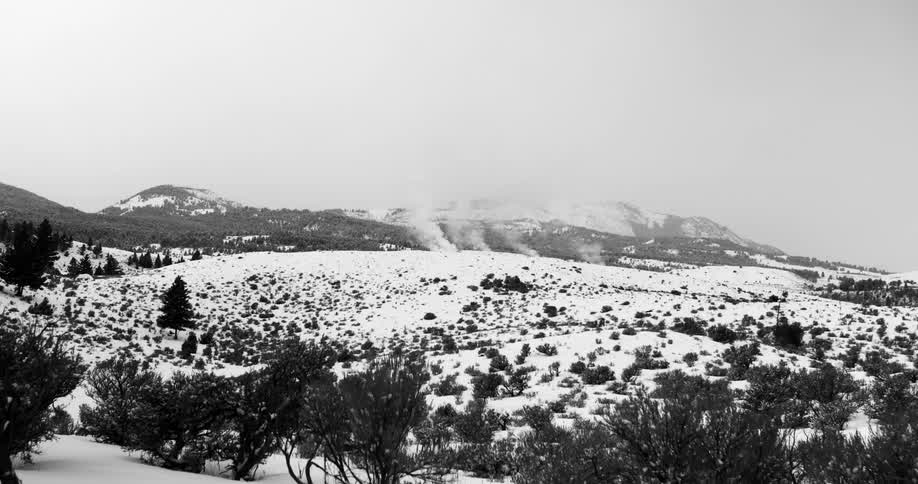Fog flows off mountains onto snow covered plains