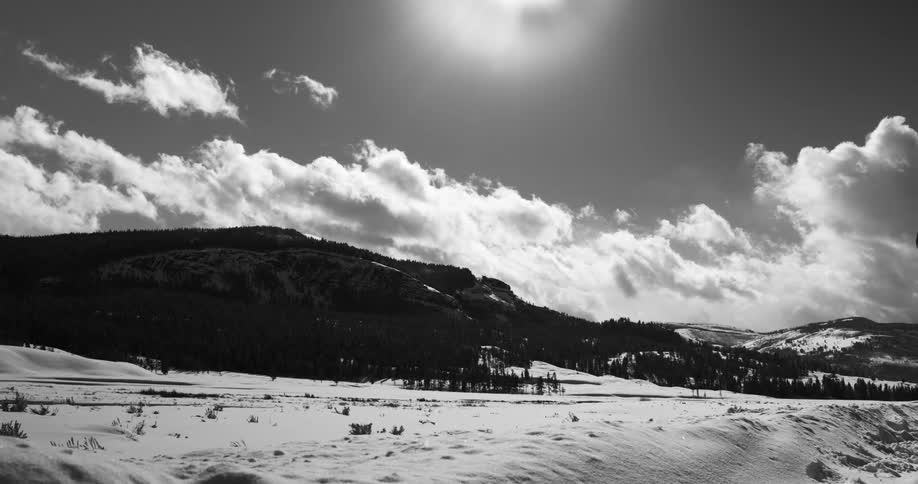 Clouds travel over the mountains and snowy land