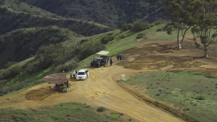 People stand around two vehicles on top of a large mountain top