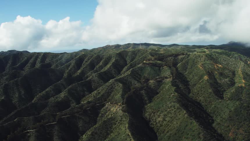 Clouds hover over area of vegetation covered mountains terrain