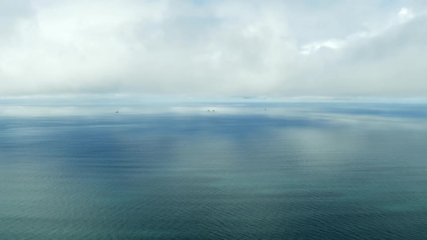 Vast expanse of bright blue ocean under cloudy sky