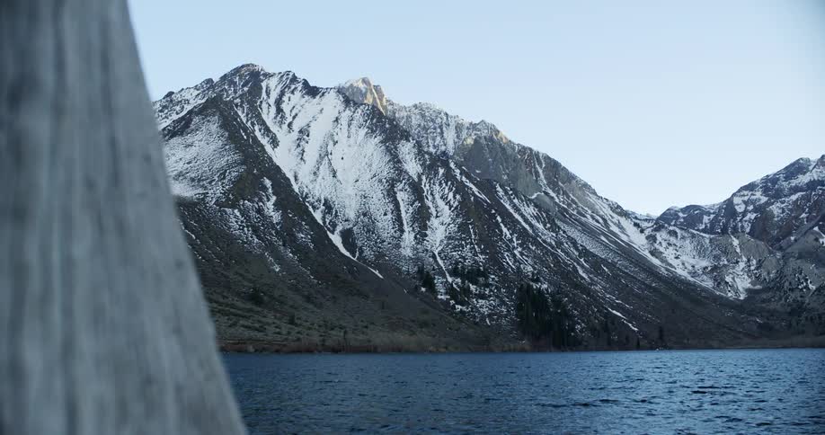 Snow covered mountains border rippling water under clear sky