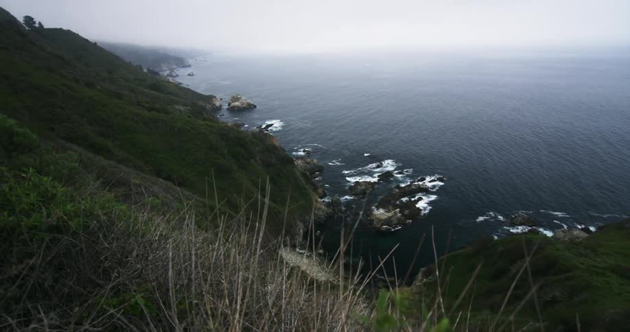 Ocean waves crash on the rocks in the coast of a mountain range