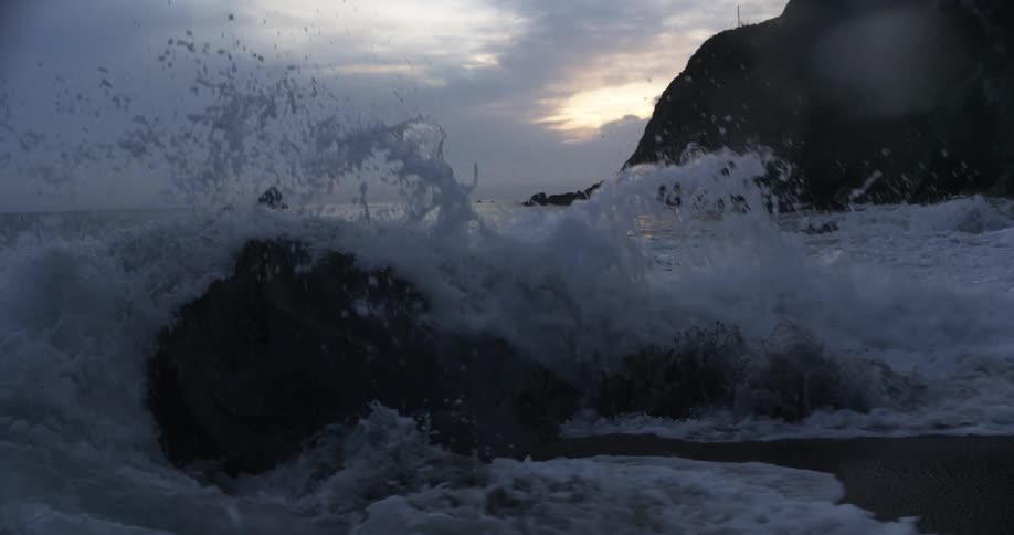 Wave crashes against rock on beach