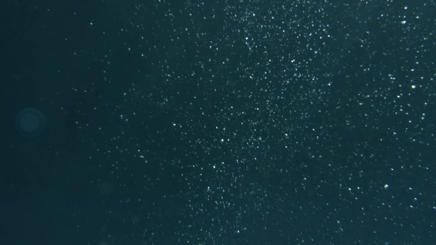 Underwater with light reflection on sea floor and bubbles rising to surface