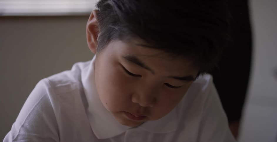 Boy writing on a notebook in a classroom