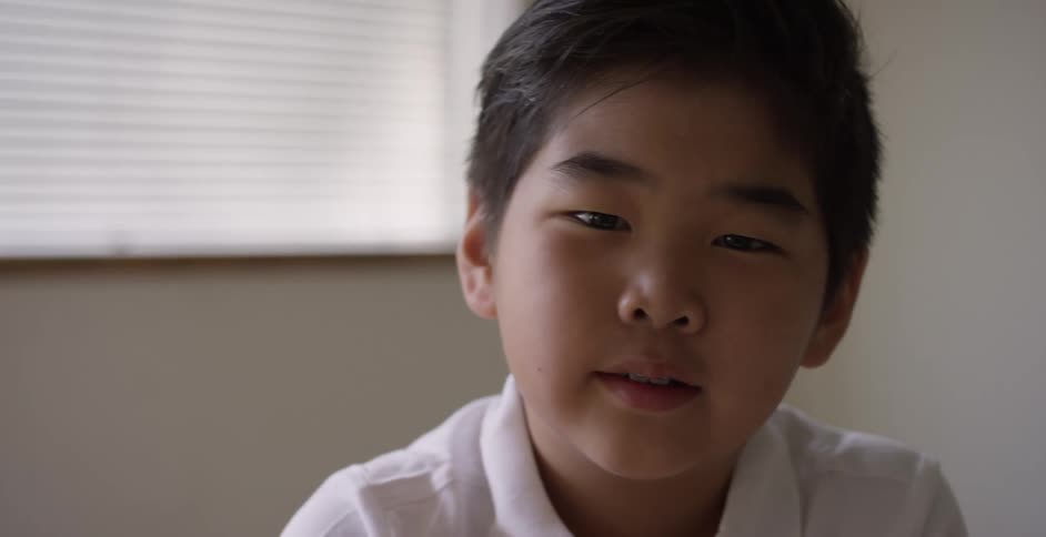 Young boy lifts head up to speak towards camera