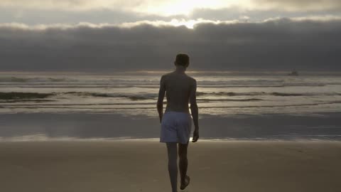 A man slowly walks over to the water at the beach