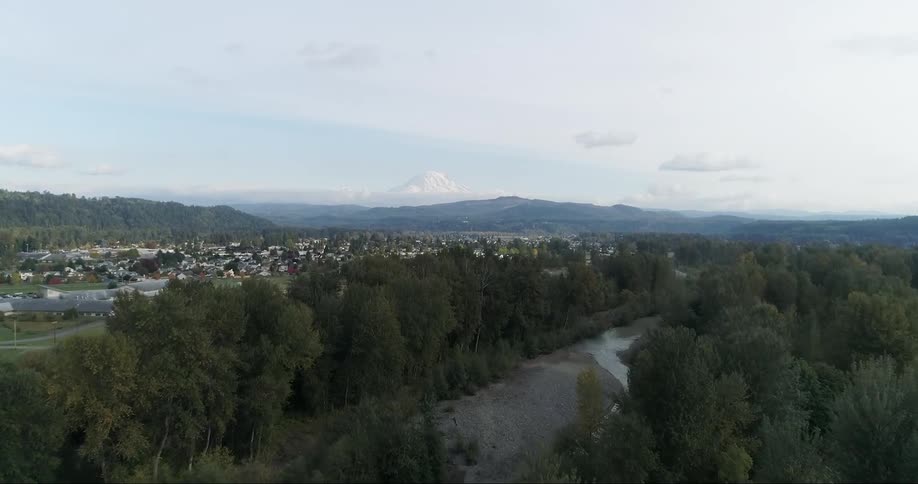 A dense neighborhood sits between a forest and mountains