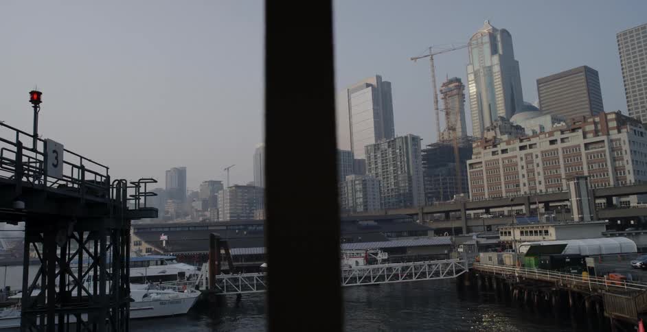 Boats in the pier next to the skyscrapers of a waterfront city at morning