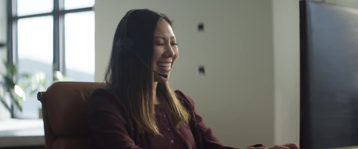 Woman in front of a computer talks into a headset in a call center