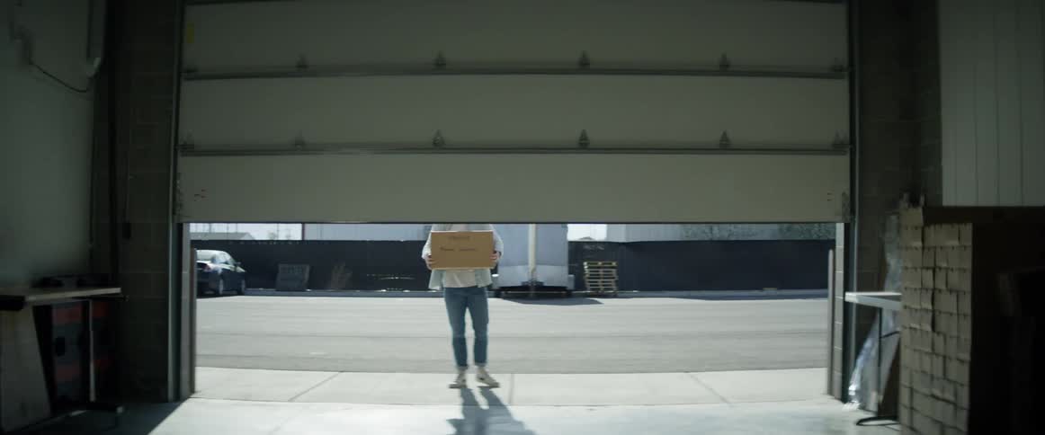 Man opens a garage door and carries a box of medical supply