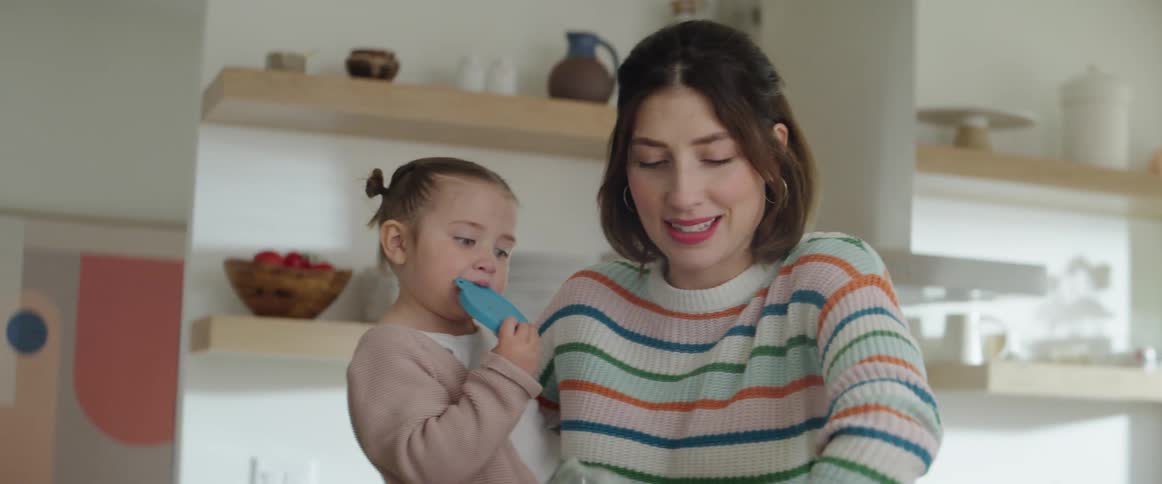 Mother talking to child she is holding while unpacking groceries