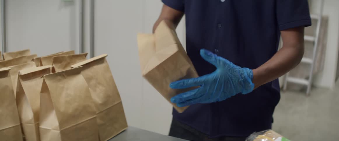 A person is unfolding a paper sack