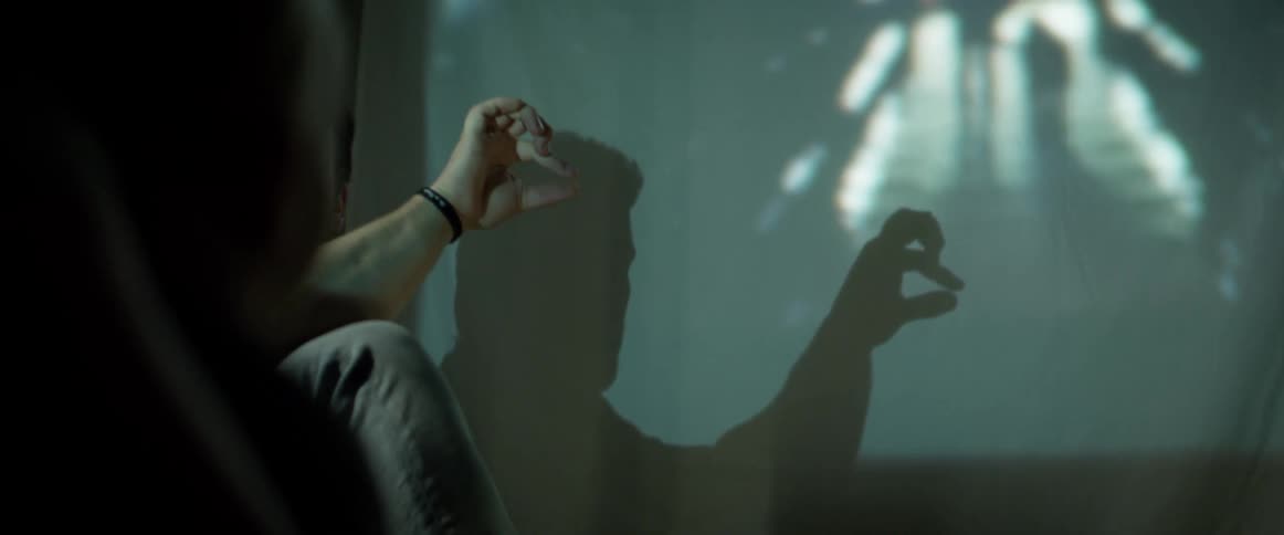 Father plays with son projecting shadow animals in a wall with his hand