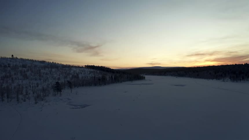 Snow covered field and forests at dusk