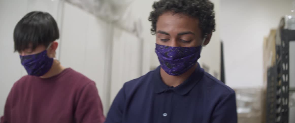 Young men wearing face masks working in a warehouse